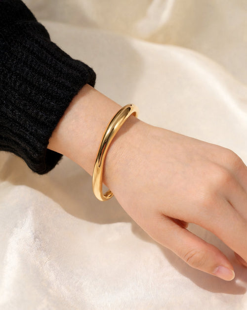 The Twist Cuff in gold, worn on the wrist