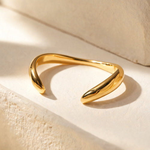 The Twist Cuff in gold, open sculptural cuff on ivory plaster